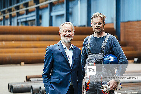 Male manager standing with warehouse worker at metal industry