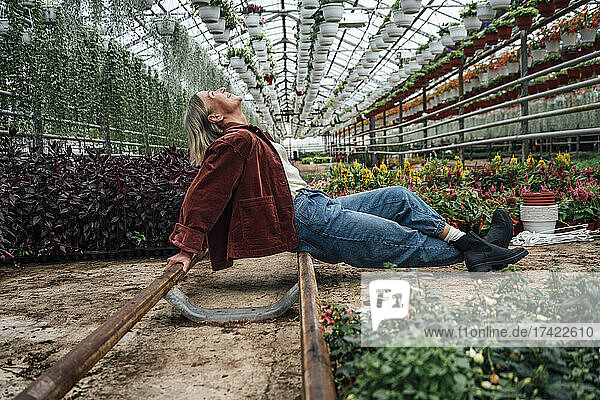 Carefree female farmer sitting with legs crossed at ankle in greenhouse