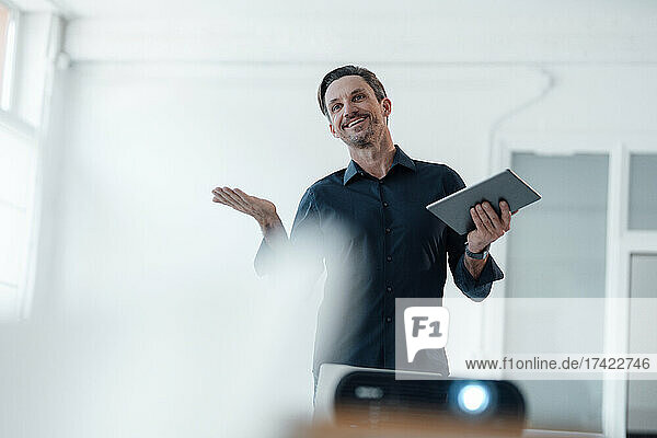 Smiling businessman with digital tablet during presentation in board room