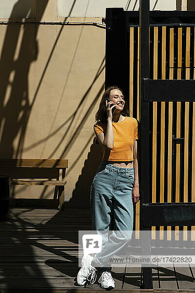 Smiling woman talking on mobile phone during sunny day
