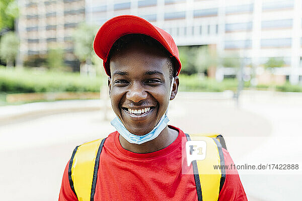 Smiling delivery man wearing red hat during COVID-19