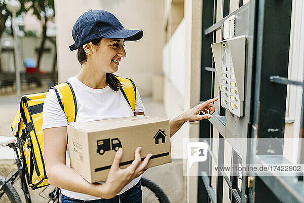 Delivery woman holding box while standing at gate