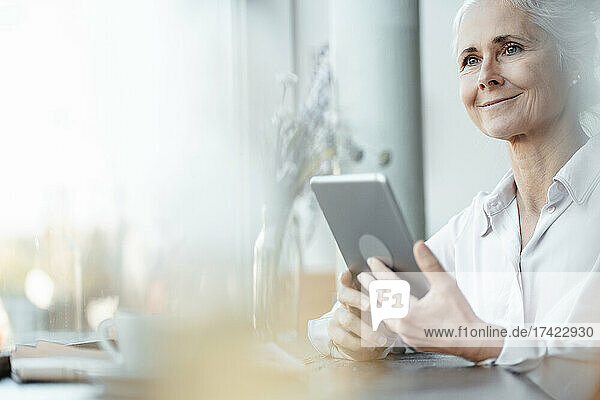 Smiling businesswoman with digital tablet in coffee shop
