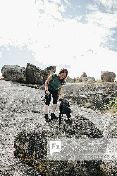 Smiling woman and dog standing on rock