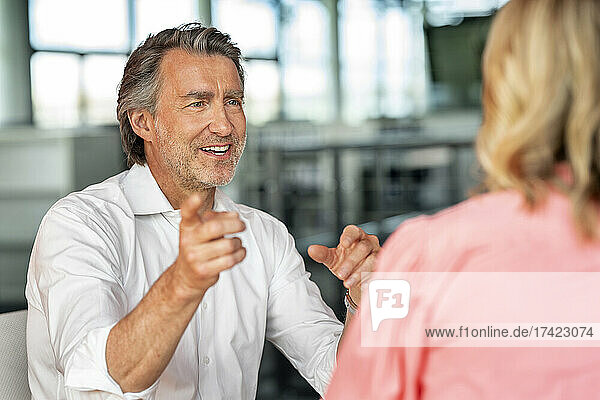 Mature businessman gesturing while talking with female colleague in office