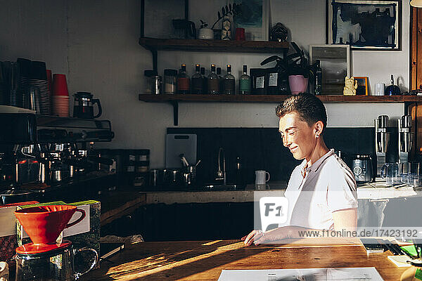Smiling female barista at coffee shop during sunny day