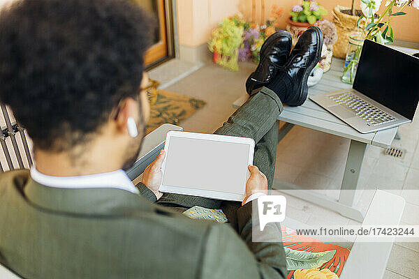 Male business professional using digital tablet while sitting at home