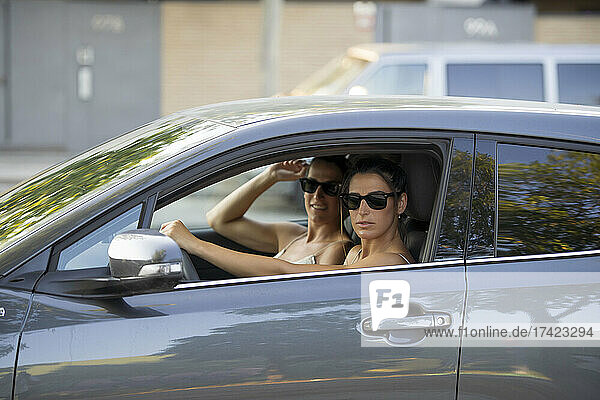 Mid adult twin sisters wearing sunglasses in car