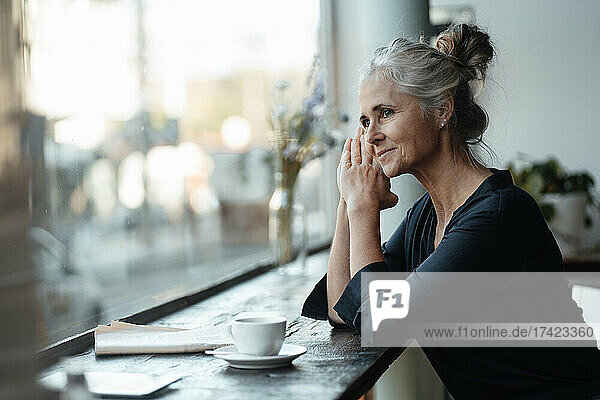 Nachdenkliche Frau sitzt am Tisch im Café am Glasfenster