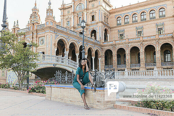 Happy female tourist sitting on bench at Plaza De Espana  Seville  Spain