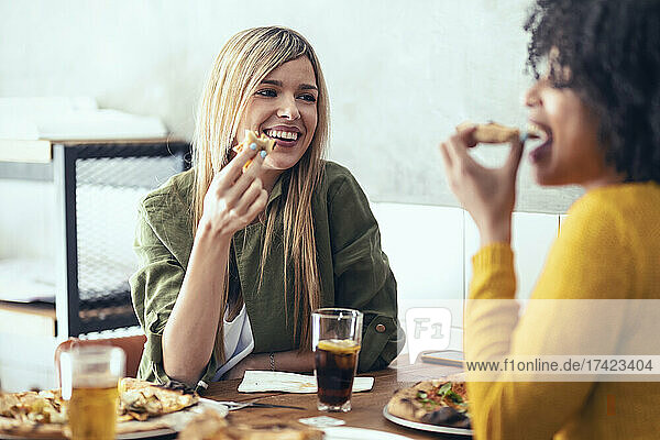 Female friends eating pizza in restaurant