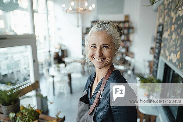 Smiling female entrepreneur wearing apron in cafe