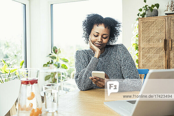 Afro female freelancer using smart phone at home office