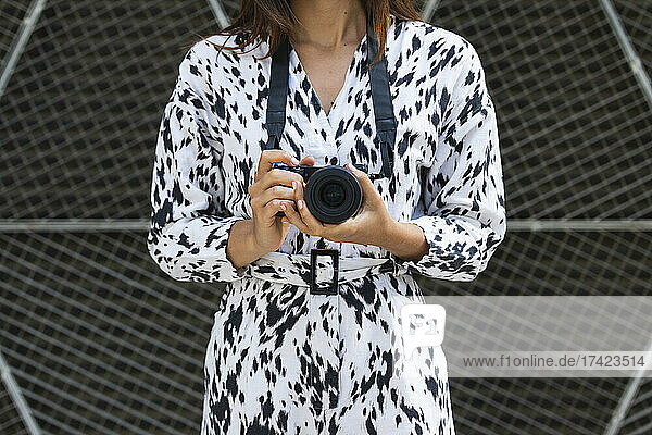Woman holding camera in front of fence