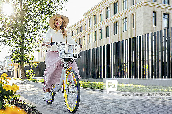 Smiling woman riding bicycle on footpath