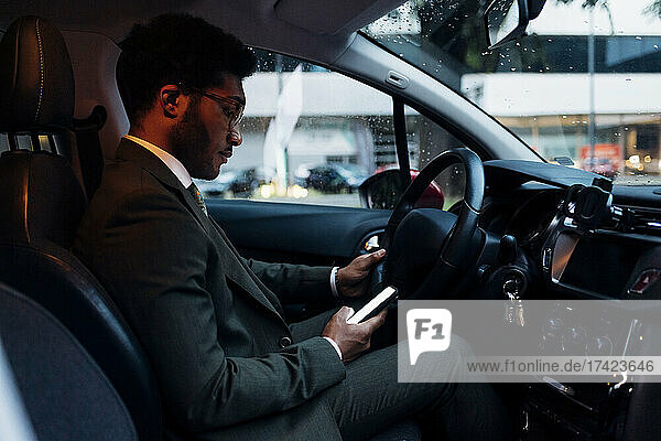 Young businessman using mobile phone while sitting in car