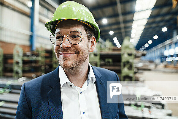 Smiling male professional with hardhat in factory