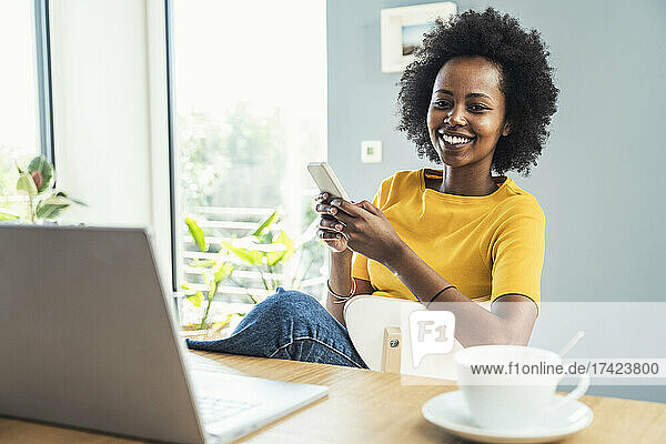 Female freelancer holding smart phone at home office