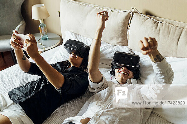 Junge schwule Frauen genießen die virtuelle Realität  während sie zu Hause im Bett liegen