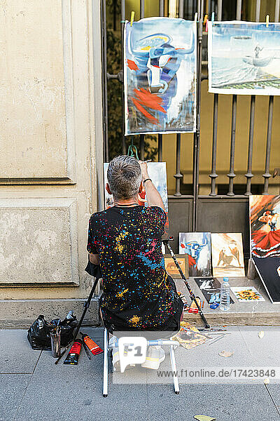 Male street artist painting on footpath