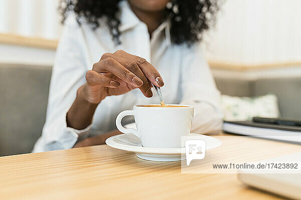 Businesswoman stirring spoon in coffee cup at cafe