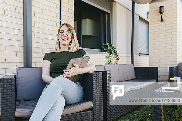 Smiling female professional holding digital tablet while sitting on chair