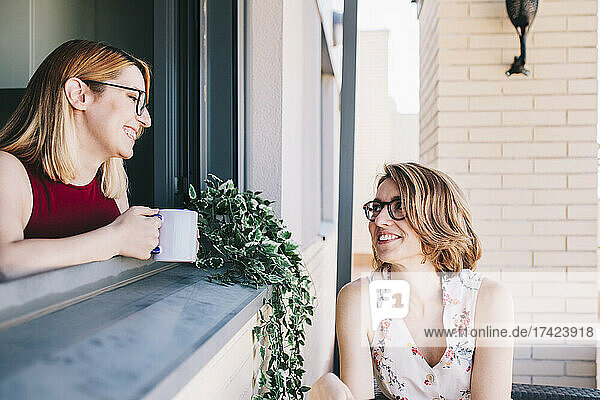 Smiling businesswoman holding coffee cup while looking at female colleague