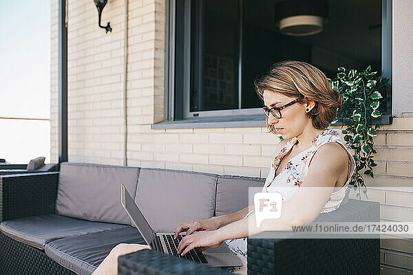 Geschäftsfrau mit Brille benutzt Laptop  während sie auf dem Sofa sitzt