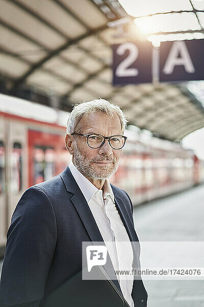 Businessman wearing eyeglasses standing on railroad station platform