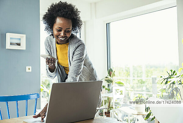 Afro businesswoman working on laptop at home