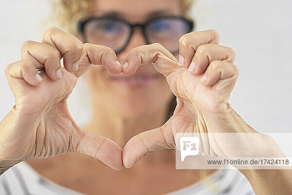 Mature woman making heart shape with hands