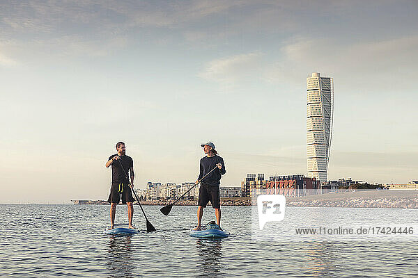 Man talking with male instructor while paddleboarding in sea
