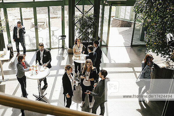 Blick von oben auf Geschäftsleute und Geschäftsfrauen  die beim Networking im Kongresszentrum zusammenstehen und diskutieren
