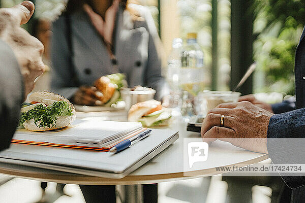 Geschäftsfrau mit Geschäftsmann am Tisch stehend beim Essen während einer Netzwerkveranstaltung im Kongresszentrum