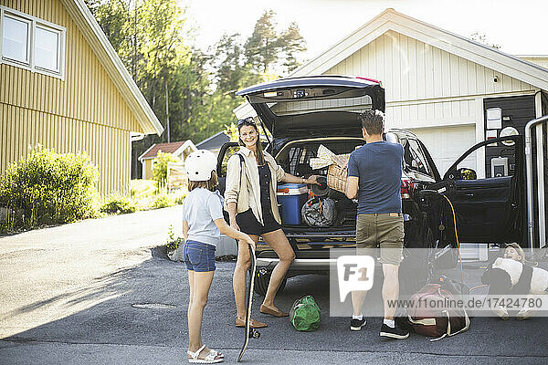 Porträt einer Mutter  eines Vaters und zweier Töchter  die neben einem Auto an einer Ladestation für Elektrofahrzeuge stehen