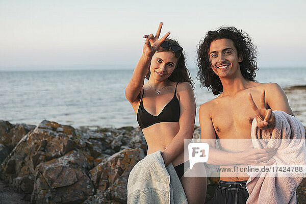 Porträt eines jungen Paares mit Friedenszeichen am Meer
