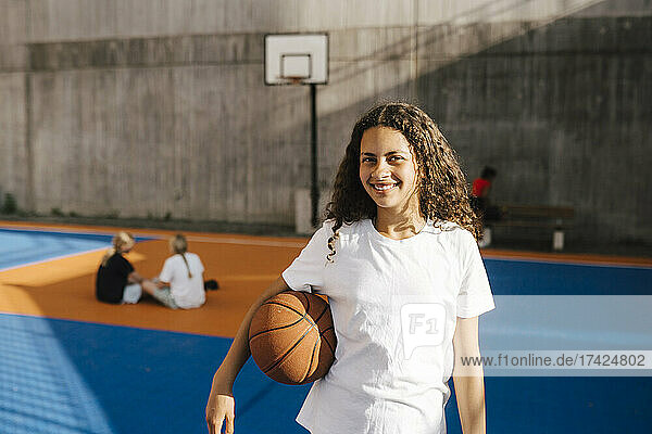Lächelndes Mädchen mit Basketball auf dem Basketballplatz