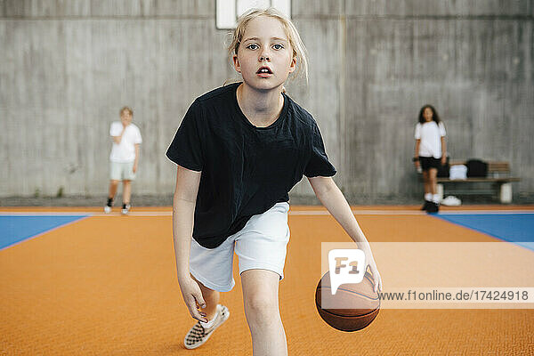 Portrait of female basketball player practicing at sports court