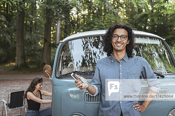 Porträt von lächelnden Mann mit Smartphone gegen Camping van