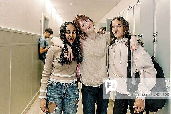 Porträt von lächelnden Teenager-Mädchen  die im Schulkorridor stehen