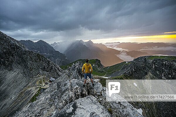 Hikers at the summit of the Westliche Törlspitze  in the background cloudy mountains at sunset with dramatic light  view of Frauenalpl  Wetterstein Mountains  Garmisch Partenkirchen  Bavaria  Germany  Europe