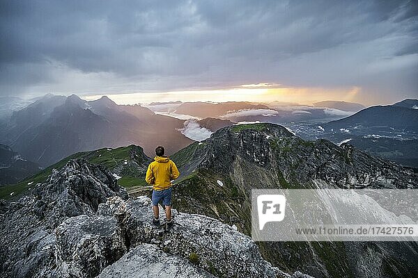 Hikers at the summit of the Westliche Törlspitze  in the background cloudy mountains at sunset with dramatic light  view of Frauenalpl  Wetterstein Mountains  Garmisch Partenkirchen  Bavaria  Germany  Europe