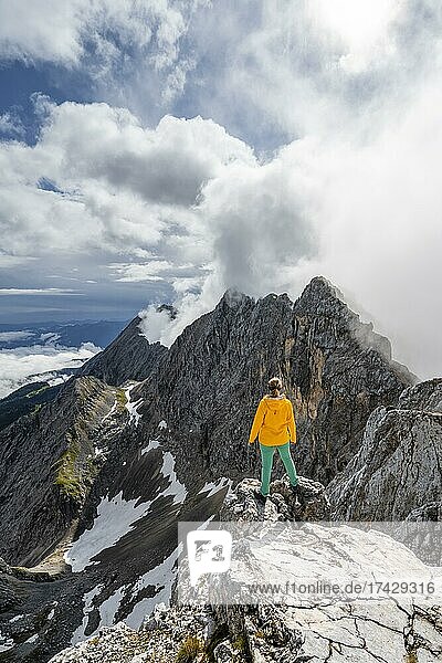 Wanderin auf einem Gipfel  Westliche Törlspitze  Berge bei dramatischen Wolken  Wettersteingebirge  Garmisch-Partenkirchen  Bayern  Deutschland  Europa