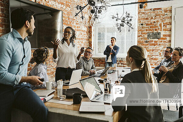 Geschäftsleute schauen auf eine Unternehmerin  die ihr Produkt bei einem Treffen im Büro erklärt