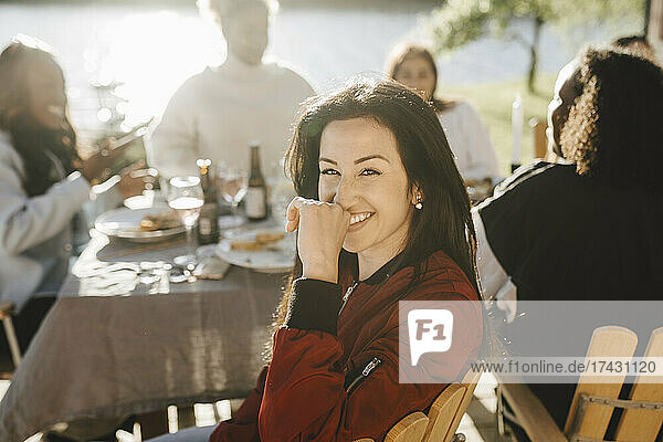 Junge Frau lächelt  während sie mit Freundinnen auf einer Party sitzt