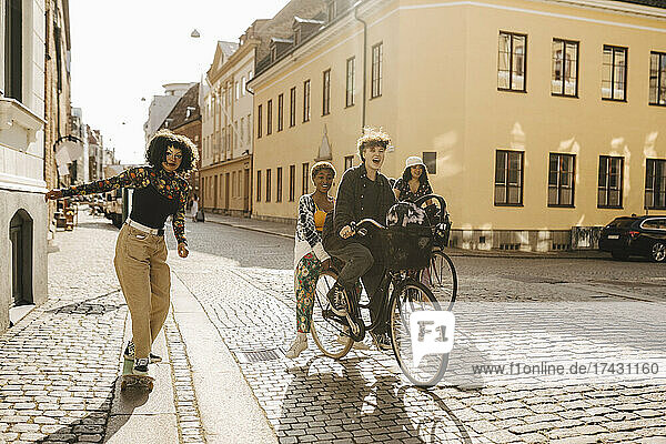 Fröhliche Freunde auf dem Fahrrad und Skateboard in der Stadt