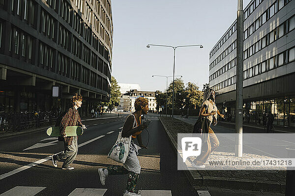 Glückliche multirassische Freunde laufen beim Überqueren der Straße in der Stadt