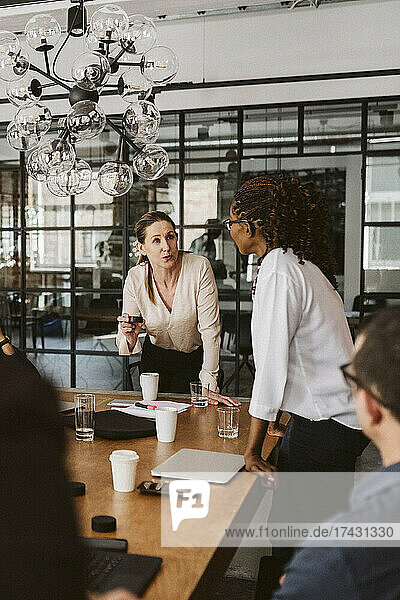 Geschäftsfrau erklärt männlichen und weiblichen Kollegen während einer Sitzung im Sitzungssaal ein Produkt