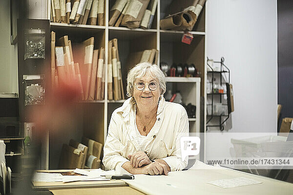 Lächelnde Handwerkerin lehnt sich im Büro über den Tisch