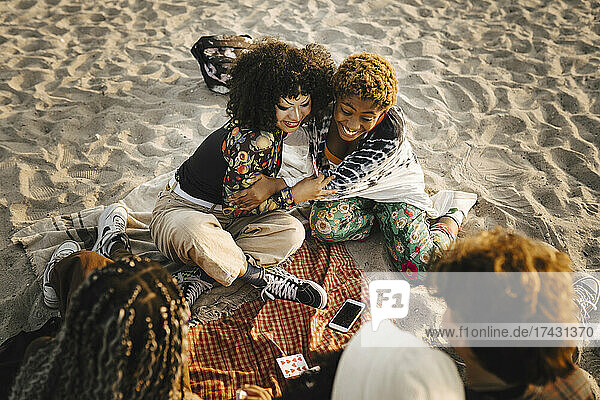 Lächelndes Mädchen im Teenageralter umarmt nicht-binären Freund am Strand